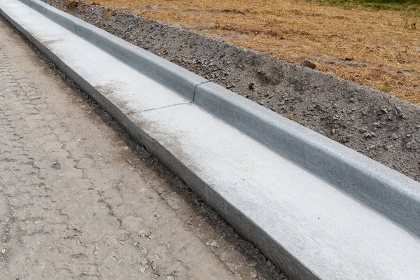 Yol yapımı detaylar, yeni hazırlanmış yol yatağının yanında beton kaldırım, yatay görünüm.