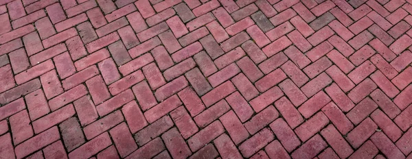 Perspective view background of bricks laid in a herringbone pattern, red brick in wide backdrop, horizontal aspect