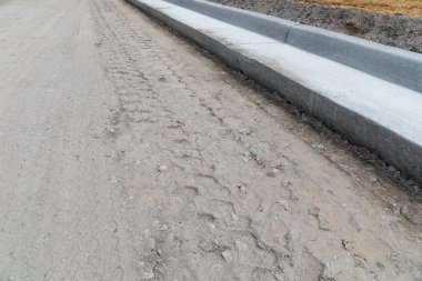 Yeni çıkarılmış beton kaldırımın, sokak inşaat alanının, yatay görünümün yanına yeni derecelendirilmiş yol yatağı.