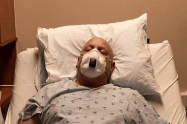 Old bald man in a respirator in a hospital bed asleep on a pillow, coronavirus, cancer, chemotherapy, horizontal aspect clipart