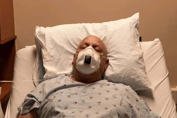 Old bald man in a respirator in a hospital bed asleep on a pillow, coronavirus, cancer, chemotherapy, horizontal aspect
