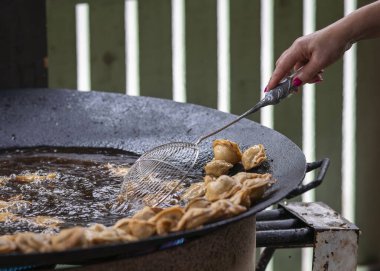 Pelmeni (hamur köfteleri) şehir yemek festivalinde ızgara tavasında kızartılıyor. Aşçı ızgarada lezzetli pelmeni pişiriyor..