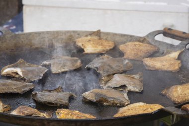 Kızarmış dil balığı - geleneksel deniz ürünleri - panayırda büyük bir kızartma tavasında. Sıcak tavada pisi balığı pişiriyorum..
