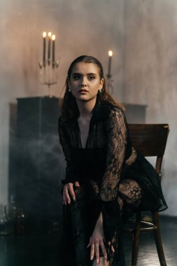 Siyah dantelli gizemli kadın dumanlı, gotik bir ortamda klasik bir piyanonun yanında poz veriyor. Yüksek kalite fotoğraf