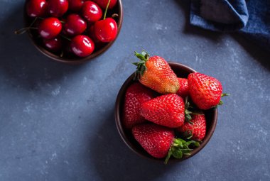 Yaz çilek ve kiraz ahşap plakalar mavi beton içinde arka plan, sağlıklı gıda kavramı masa 