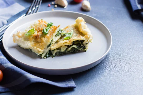 Ricotta peyniri ve mavi taş concreet tablo arka plan üzerinde ıspanak ile lezzetli ev yapımı lazanya. Vejetaryen yiyecekler. Italyan Mutfagi