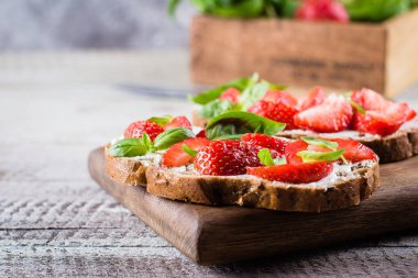 Süzme peynir, fesleğen ve eski püskü tablo arka plan üzerinde ahşap tahta üzerinde üzerinde çilek çilek bruschetta. kopya alanı