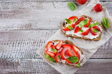 Yaz Aperatif yiyecek. Süzme peynir, fesleğen ve eski püskü ahşap masa arka plan, üstten görünüm, kopya alanı kagit üzerinde çilek çilek bruschetta