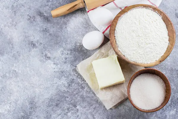 Pişirme kek, pasta, kurabiye pasta için malzemeler: un, yumurta, şeker, tereyağı, PIN ve gri beton tablo arka plan üzerinde haddeleme. Üstten görünüm, kopya alanı