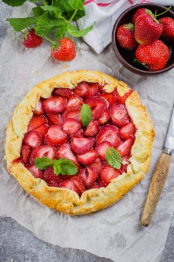 Galette'ye gri Beton taş zemin üzerine çilek ile. Vejetaryen Sağlıklı berry tart taze dilimlenmiş çilek ve nane ile dekore edilmiştir. Lezzetli yaz Yemek Tatlilar.