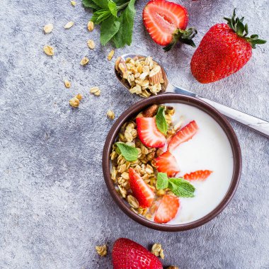 Yoğurt, müsli ve gri beton tablo arka plan üzerinde çilek granola ile kahvaltı. Sağlıklı Vegan temiz diyet gıda kavramı. Görünümü ana sayfa, yer kopyalayın, yat