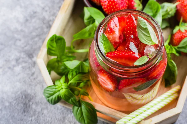 Summer Food and Drink. Lemonade with Strawberry and Basil in mason jar on wooden tray on concrete table. Top view, copy space
