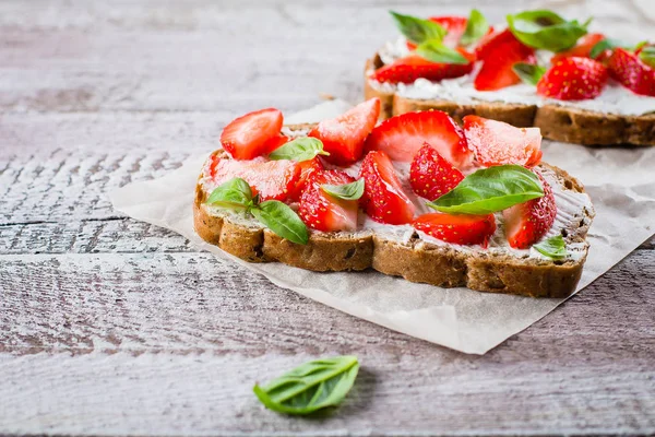Süzme peynir, fesleğen ve eski püskü ahşap masa arka plan, üstten görünüm, kopya alanı kagit üzerinde çilek çilek bruschetta. Yaz yemek yiyecek.