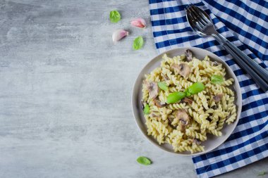 Makarna Fusili mantar, sause krem ve fesleğen taş beton masada. İtalyan gıda kavramı. Üstten görünüm, kopya alanı