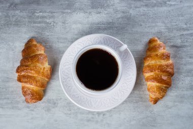 İle kruvasan gri tablo arka plan üzerinde siyah kahve.