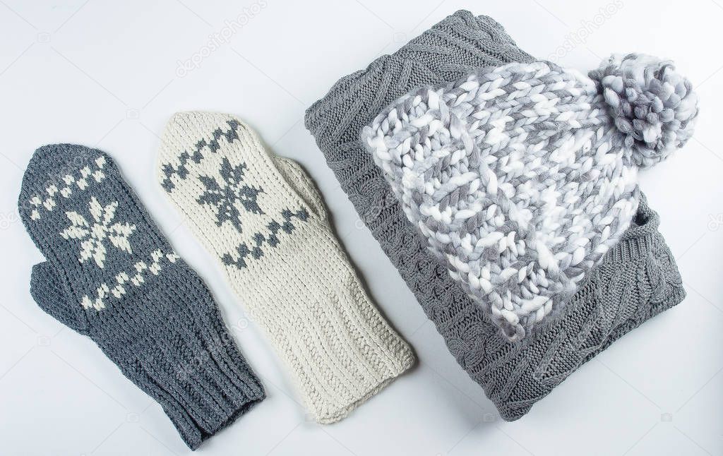Collection of woolen knitted sweater, mittens, hat on white background table