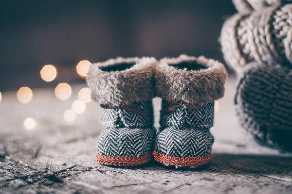 Διακοπές Χριστούγεννα μωρό παιχνίδι μικρές μπότες και στοίβα σωρό άνετα πλεκτά πουλόβερ και το ξύλινο τραπέζι υπόβαθρο. Ζεστός Cozy έννοια. Χιόνι τονωτική εικόνας — Φωτογραφία Αρχείου