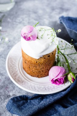 Paskalya kek kulich. Geleneksel Paskalya tatlı ekmek beze ve gri taş tablo arka plan üzerinde plaka üzerinde pembe gül dekore edilmiştir. Kopya alanı.