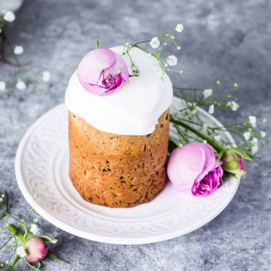 Paskalya kek kulich. Geleneksel Paskalya tatlı ekmek beze ve gri taş tablo arka plan üzerinde plaka üzerinde pembe gül dekore edilmiştir. Kopya alanı.