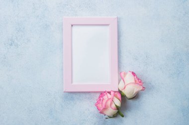 Yaratıcı minimalizm düz fotoğraf çerçevelemek ve pembe güller mavi zemin üzerine yatırın. Sevgililer günü, anne ve bahar kavramı. Mockup kavramı