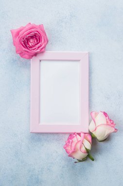 Yaratıcı minimalizm düz fotoğraf çerçevelemek ve pembe güller mavi zemin üzerine yatırın. Sevgililer günü, anne ve bahar kavramı. Mockup kavramı