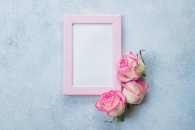 Yaratıcı minimalizm düz fotoğraf çerçevelemek ve pembe güller mavi zemin üzerine yatırın. Sevgililer günü, anne ve bahar kavramı. Mockup kavramı
