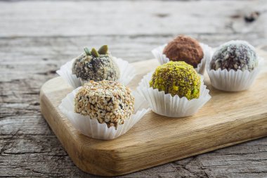 Kurutulmuş meyve ve fındık Hindistan cevizi cips, kakao, keten tohumu, fıstık, susam ile sağlıklı enerji toplar yaptı. Çiğ vegan şeker ahşap tahta üzerinde