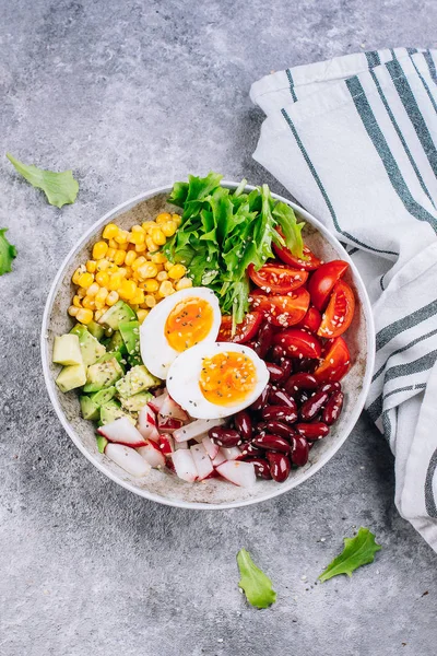 Tigela de almoço vegan saudável. Abacate, ovo, feijão vermelho, tomate, rabanete, milho, folhas verdes salada de legumes. Concreto. Vista superior. Espaço de cópia — Fotografia de Stock