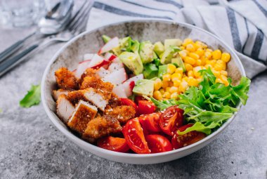 Sağlıklı öğle yemeği Biddha kase. Avokado, tavuk, domates, turp, Mısır, yeşil yaprakları sebze salatası. Beton arka plan. Yakın çekim