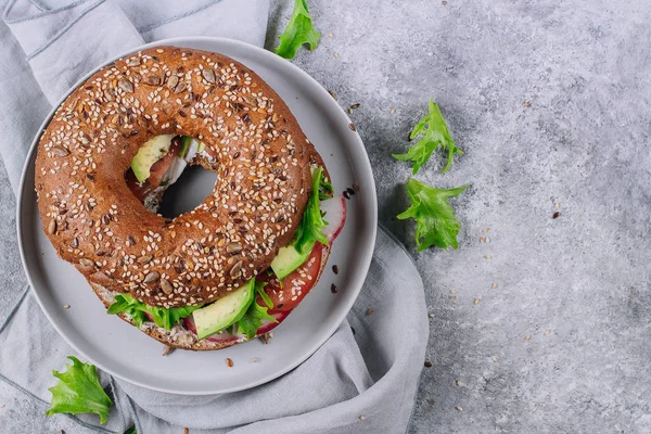 Bagels Veggie com abacate, tomate, rabanete e folhas verdes em chapa escorregadia sobre fundo mesa de concreto. Almoço saudável. Delicioso conceito de comida equilibrada. Vista superior, espaço de cópia — Fotografia de Stock