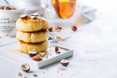 Süzme peynir lezzetli bal ve karışık Kuruyemiş ile krep. Syrniki, lor börek. Beyaz beton zemin. Kopya alanı