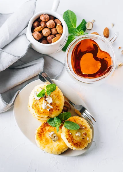 Snídaně nebo oběd koncept. Tvarohové palačinky s medem, ořechy a máta na bílém pozadí. Pohled shora — Stock fotografie