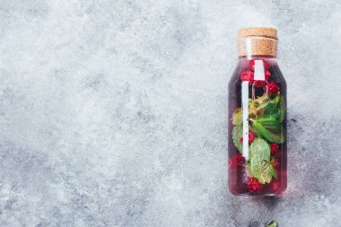 Ev yapımı ahududu nane Siyah frenk üzümü limonata cam şişede. Yaz sağlıklı içecek kavramı, gri beton zemin üzerine su infüzyon. Üstten Görünüm kopya alanı