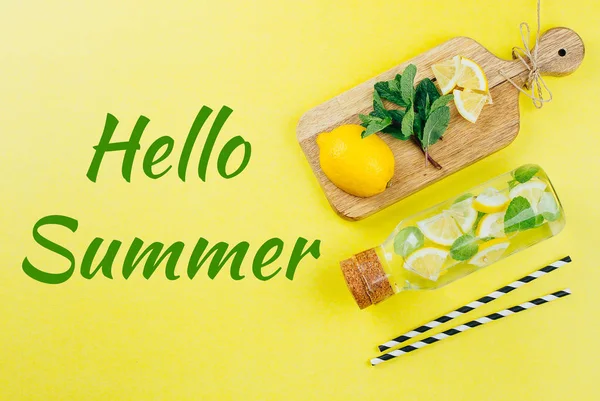 Hallo zomer Card. Lemon Mint water of limonade in glazen fles en ingrediënten op houten snijplanken op gele tabelachtergrond. Zomer drinken Concept — Stockfoto