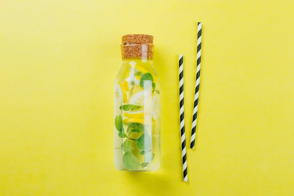 Limón Menta Agua o limonada en botella de vidrio y tubos de papel sobre fondo de mesa amarillo. Concepto de bebida de verano — Foto de Stock