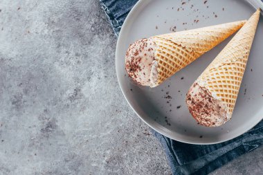 Tatlı çikolatalı dondurma koni gri beton zemin üzerine plaka üzerinde. Üstten Görünüm.