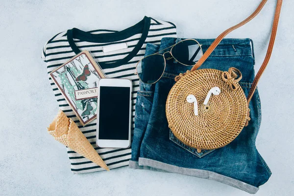 Flat lay with summer women's clothing and accessories. Striped t-shirt, blue denim shorts, fashionable organic rattan bag. Vacation, travel concept. Top view — Stock Photo, Image