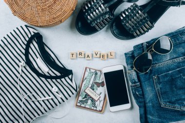 Seyahat düz yatıyordu. Bahar ve yaz kadın giyim ve aksesuarları. T-shirt, yaz sandal, çizgili mavi kot şort, moda organik rattan çanta. Tatil, seyahat kavramı. Üstten Görünüm