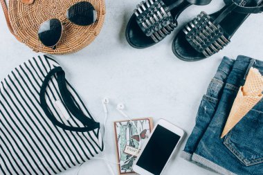 Casual kadın giyim ve aksesuarları. T-shirt, yaz sandal, çizgili mavi kot şort, moda organik rattan çanta. Tatil, seyahat kavramı. Üstten Görünüm, kopya alanı