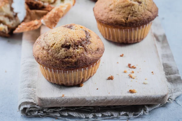 Zelfgemaakte zoete chocolade vanille muffins van twee soorten deeg met glas en een fles melk op houten tafel achtergrond. Ruimte kopiëren — Stockfoto