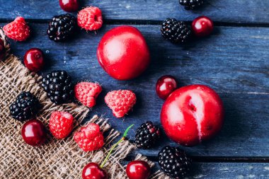 Yemek geçmişi. Yaz ve Sonbahar taze çilek ve mavi ahşap masa arka plan üzerinde meyve. Kopya alanı. Ahududu, böğürtlen, kiraz ve erik - Üst görünümü lezzetli Vejetaryen gıda. Rustik stil
