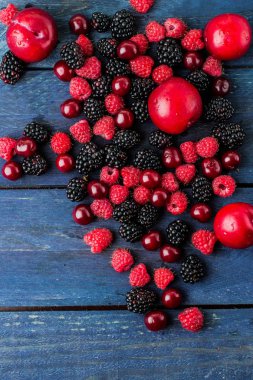 Yemek geçmişi. Mavi ahşap masa arka plan üzerinde yaz taze çilek. Kopya alanı. Üst görünüm Vejetaryen gıda - ahududu, böğürtlen ve kiraz. Rustik stil