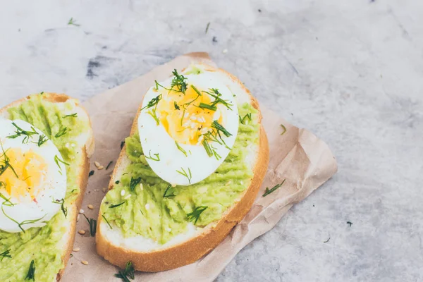 Здоровый тост со сливками авокадо и яйцом на сером мраморном фоне. Горизонтальное изображение, скопировать пространство. Вегетарианское питание — стоковое фото
