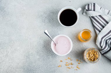 Sağlıklı Kahvaltı Konsepti. Çilek veya ahududu yoğurt, granola, bal ve hafif beton masa arka plan kahve fincan. Kopyalama alanı ile yukarıdan görüntüleyin. Düz yatıyordu