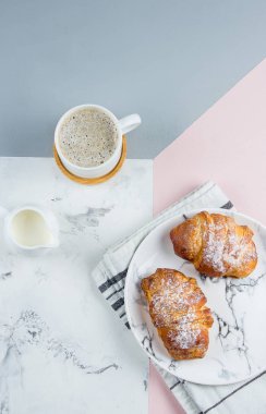 Bir kağıt torba ve üç renkli arka plan üzerinde kahve fincan iki taze kruvasan, üst görünüm, kopya alanı, düz yatıyordu