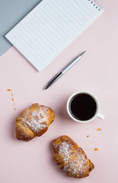 Taza de café con croissants y cuaderno vacío y pluma para el plan de negocios y las ideas de diseño sobre fondo bicolor desde arriba. Plan matutino. Plano concepto laico — Foto de Stock