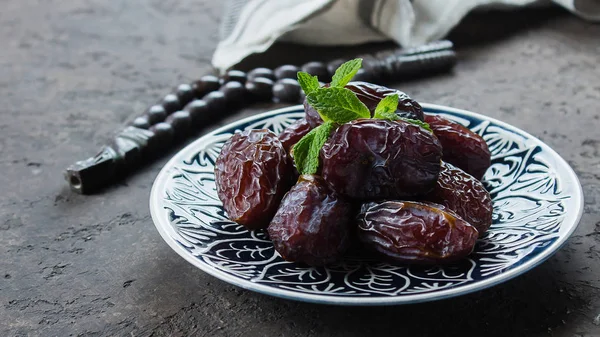 Ramadan Kareem Food concept. Verse dadels, rozenkrans kralen en thee op donkere betonnen achtergrond. Banner afbeelding — Stockfoto