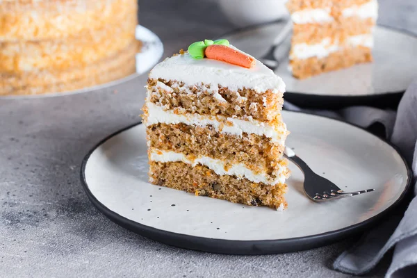 Segment van zelfgemaakte worteltaart met roomkaas glazuur op plaat op grijze stenen tafel achtergrond — Stockfoto