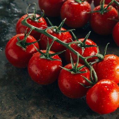 Fresh cherry tomatoes on a dark brown background