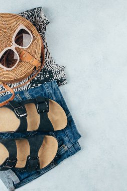 Düz yaz kadın giyim ve aksesuarları ile yatıyordu. Hayvan baskılı t-shirt, mavi kot şort, moda organik rattan çanta, güneş gözlüğü. Tatil, seyahat konsepti. Üstte görüntü